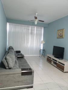 a living room with a couch and a flat screen tv at Apartamento PÉS NA AREIA in Santos