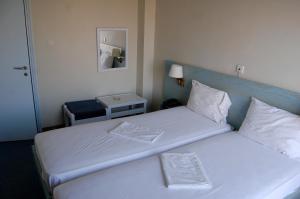 a bedroom with two beds with a blue headboard at Astir Hotel in Karlovasi