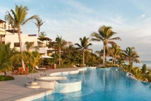 a pool at a resort with palm trees and the ocean at Spectacular Beachfront at veneros fully staffed in Cruz de Huanacaxtle