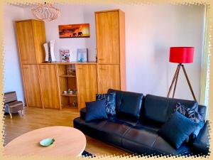 a living room with a black leather couch and a table at Résidence des lentilles in Schiltigheim