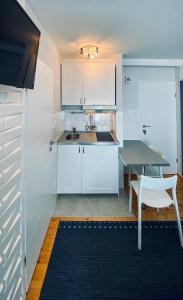 a kitchen with white cabinets and a table and a sink at Komiza Provita Guesthouse in Komiža