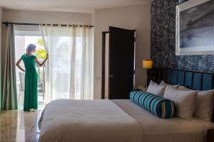 a woman in a green dress is looking out the window at Corazón Cabo, a Noble House Resort in Cabo San Lucas