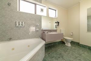 a bathroom with a tub and a toilet and a sink at Legends Motel in Palmerston North