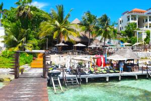 a dock with chairs and umbrellas on a beach at Hotel Boutique Skulls Landing in Isla Mujeres
