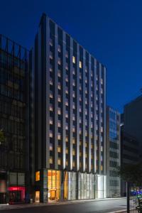 a tall black building with many windows at night at KOKO HOTEL Ginza-1chome in Tokyo