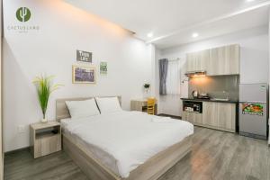 a bedroom with a large white bed and a kitchen at Cactusland Apartment in Ho Chi Minh City
