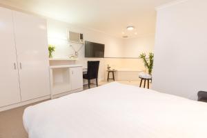 a bedroom with a white bed and a kitchen at Mildura City Gate Motel in Mildura