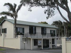 a white building with a balcony and a palm tree at Tarawhata Thermal Apartment in New Plymouth