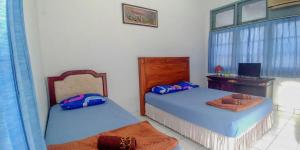 una camera con 2 letti, una scrivania e una finestra di Hotel Rajawali Mitra RedDoorz a Cirebon