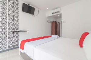 1 dormitorio con 1 cama blanca y TV en la pared en KoolKost @ Regol Park (Minimum Stay 3 Nights), en Bandung