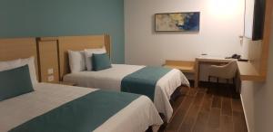 a hotel room with two beds and a desk at Hotel Plaza Sol Veracruz in Veracruz