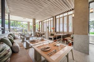 un restaurante con mesas, sillas y ventanas en VALA Hua Hin - Nu Chapter Hotels en Cha Am