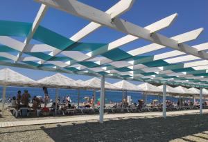 a group of people sitting under a pavilion at the beach at КИПАРИС комнаты для отпуска in Betta