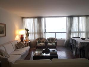 ein Wohnzimmer mit einem Sofa, Stühlen und einem Tisch in der Unterkunft COPACABANA VISTA MAR COBERTURA 2 ANDARES DE FRENTE PARA OS FOGOS DO RÉVEILLON COM 5 QUARTOS, 5 AR-CONDICIONADOS, 6 BANHEIROS e GARAGEM GRATUITA in Rio de Janeiro