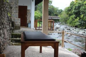 a bench sitting on a porch next to a river at Pondok Tepi Sungai in Sidemen