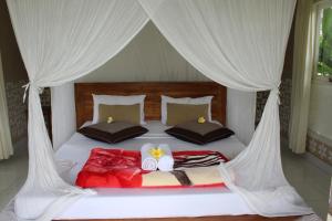 1 dormitorio con 1 cama con cortinas blancas en Pondok Tepi Sungai, en Sidemen