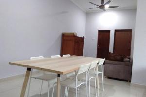 una mesa de madera con sillas blancas en una habitación en Meru Homestay suitable for up to 7 people en Klang