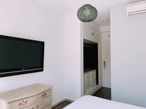 1 dormitorio con TV de pantalla plana en la pared en Boutike Guesthouse, en Sevilla