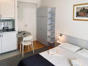 a bedroom with a bed and a desk and a kitchen at Komiza Provita Guesthouse in Komiža