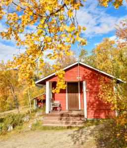 a red cabin with a chair on the porch at Kilpisjärven Retkeilykeskus Cottages in Kilpisjärvi