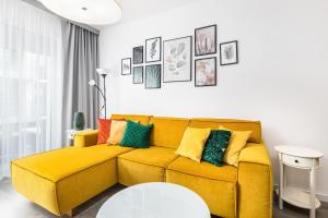 żółtą kanapę z kolorowymi poduszkami w salonie w obiekcie Jantar Apartamenty - Nadmorskie Tarasy SPA 2 w Kołobrzegu