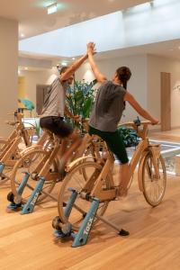 two men on bikes in a gym with their arms in the air at Coco-mat Athens BC in Athens