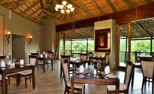 a dining room with tables and chairs and windows at Shishangeni by BON Hotels, Kruger National Park in Komatipoort