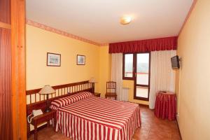 Habitación de hotel con cama y ventana en Hospedería Las Calzadas en San Vicente de la Barquera