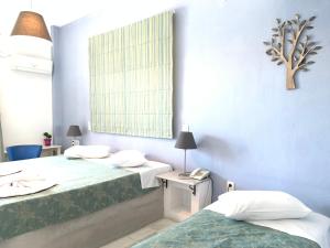 a hotel room with two beds and a window at Pandrossos Hotel - Paros in Parikia