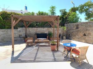 a patio with a wooden pergola and tables and chairs at Pandrossos Hotel - Paros in Parikia