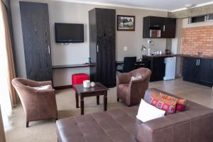 a living room with a couch and chairs and a kitchen at Dakota Lodge in Alberton +16 photos