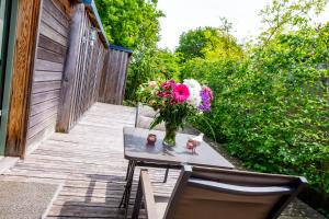 eine Vase mit Blumen auf einem Tisch auf einer Terrasse in der Unterkunft La Ferme de l'Oudon & SPA in Berville