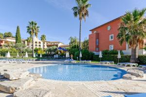 una piscina con sillas y palmeras y un edificio en Pierre & Vacances Residence Les Rivages des Issambres, en Les Issambres