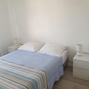 ein weißes Schlafzimmer mit einem Bett und zwei Nachttischen in der Unterkunft Cassiopée II Appt Classé 3 étoiles 2 chambres terrasse garage in Les Sables-dʼOlonne
