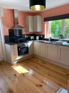 a kitchen with white cabinets and a wooden floor at Wallaby’s in Durness