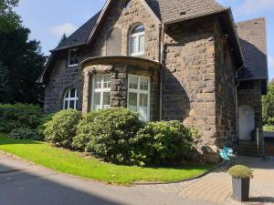 a brick house with a large window and bushes at Apartment Villa Kronenberg in Bochum