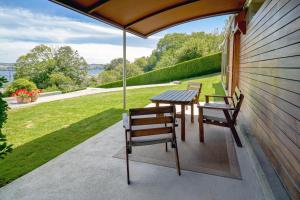 una mesa y sillas en un porche con sombrilla en Apartamento con piscina y excelentes vistas, en Ferrol