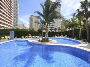 a large blue swimming pool with palm trees and buildings at ROCASOL - Beach in Calpe