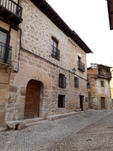 - un vieux bâtiment en pierre avec une porte en bois dans une rue dans l'établissement Sinagoga, à Peñaranda de Duero