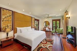 a bedroom with a large white bed and a living room at Abogo Resort Villas Luxury Da Nang in Da Nang