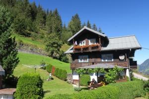 a house on a hill with people sitting on a bench in front at Appartment Brigitte in Bad Gastein
