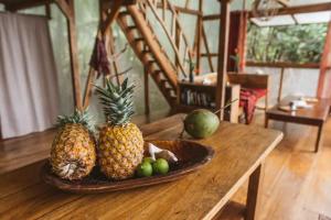 two pineapples and a plate of fruit on a wooden table at CocoVivo in Bocas del Toro