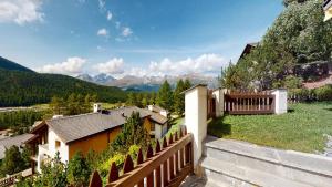 uma casa com uma cerca e montanhas ao fundo em Abitaziun Murinella - Pontresina em Pontresina