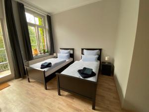 two beds in a room with two windows at Ferienwohnung König Georg in Wurzen