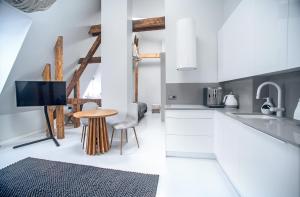 a kitchen with white cabinets and a table and a tv at Wilda Nova in Poznań