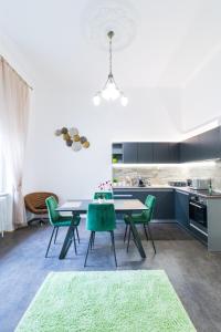 eine Küche mit einem Tisch und grünen Stühlen in der Unterkunft Gróf palace Apartman in Szeged