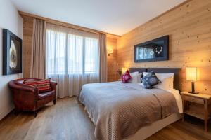 a bedroom with a bed and a chair and a window at Chalet Balthazar in Villars-sur-Ollon