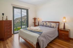 een slaapkamer met een bed, een dressoir en een raam bij OurMadeira - Casa Amaro Sol, tranquil in Calheta