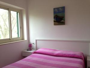 a bedroom with a pink bed and a window at Green Garden Eco-Holiday in Vieste