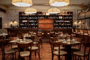um restaurante com mesas, cadeiras e garrafas de vinho em The Hoxton, Holborn em Londres